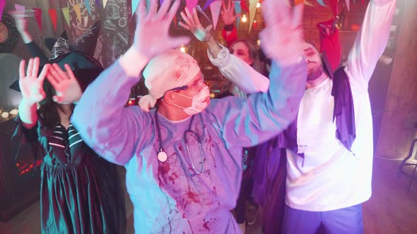 Man in Evil Doctor Costume Dancing in the Middle of a Group of Friends Celebrating Halloween