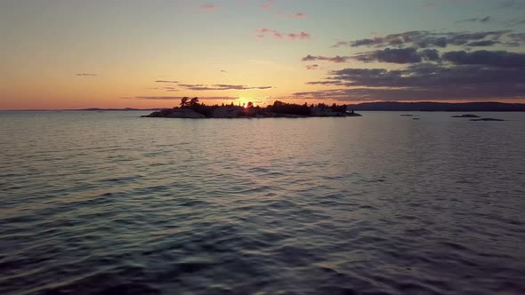 Flying Low over Waves to Island in Blue Lake at Sunset, Drone Aerial Wide Dolly In. Pine Trees, Colo