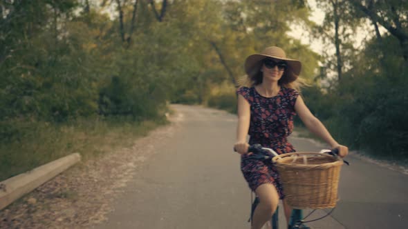 Woman Cyclist Riding On Bicycle In City Park. Woman In Hat Enjoying Summer. Bike On Countryside.
