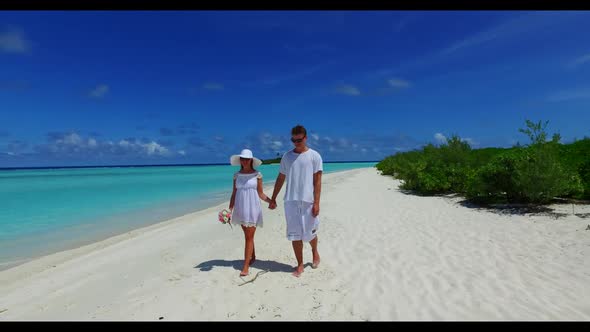 Two lovers sunbathe on idyllic bay beach adventure by transparent water with white sandy background 