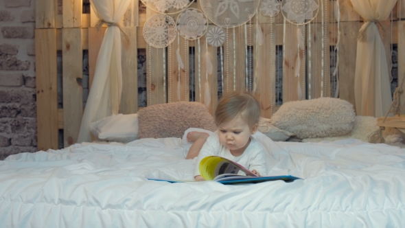 Little Girl Lying on the Bed and Reading a Book