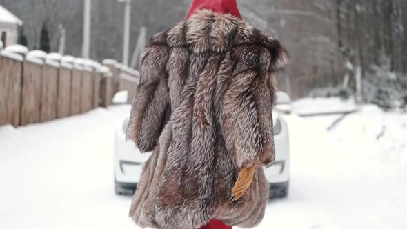 Stylish Woman in Fur Coat and Head Scarf in Winter Backyard
