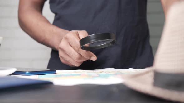 Young Man Using Magnifying Glass Looking Something on Map