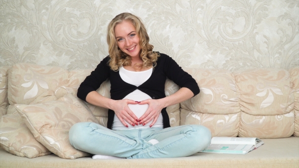 Young Happy Pregnant Woman Touching Belly and Smiling at Home