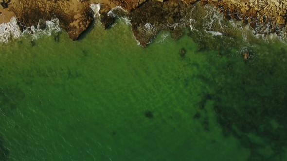 Aerial. Transparent Waves on Stone Shore in Motion