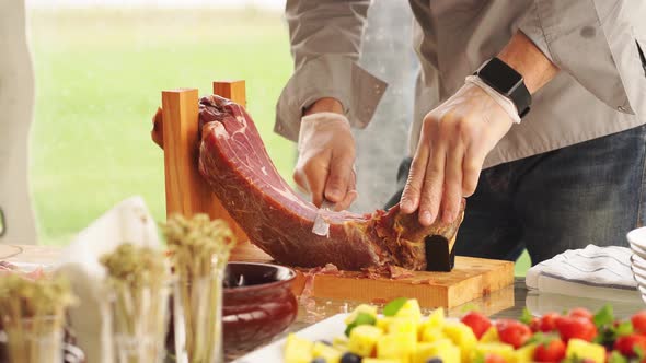 a Man in Gloves Cuts Into Thin Pieces of Dried Meat for a Banquet