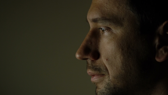 Face of a Man Sitting in the Dark in Front of a Computer Monitor