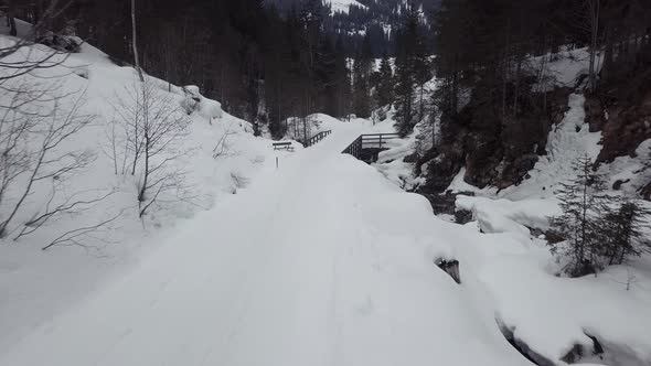 Drone flying backwards over trail in a snowy valley in the alps, Kleinwalsertal,Austria