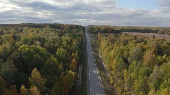 Asphalt road with traffic cars between forest in Ural