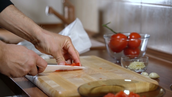 Man Cuts a Tomato for Cooking Bruschetta