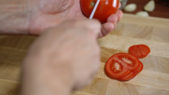 Man Cuts a Tomato for Cooking Bruschetta