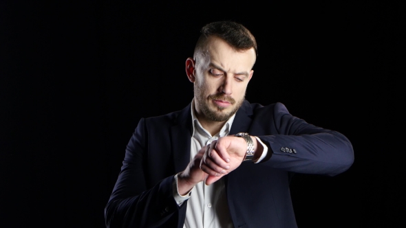 Businessman Nervously Waits and Checks the His Watch. Black Background