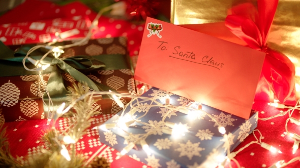 A Red Envelope with Letter To Santa Claus Is Lying Under the Christmas Tree Among Gift Boxes and