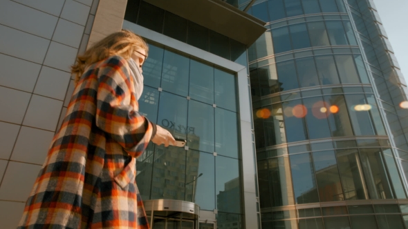 Young Woman Walking in the City Center and Receiving Message on Her Smartphone