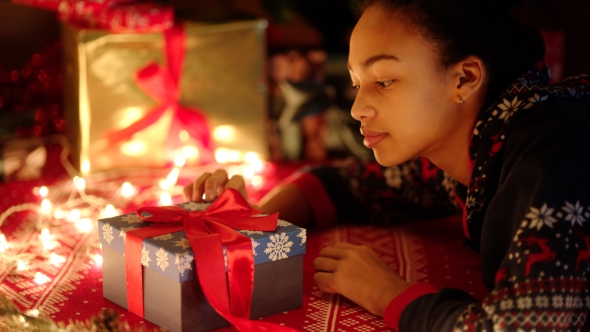 Young Black Woman Is Openning a Gift Box with Red Ribbon on Christmas Night