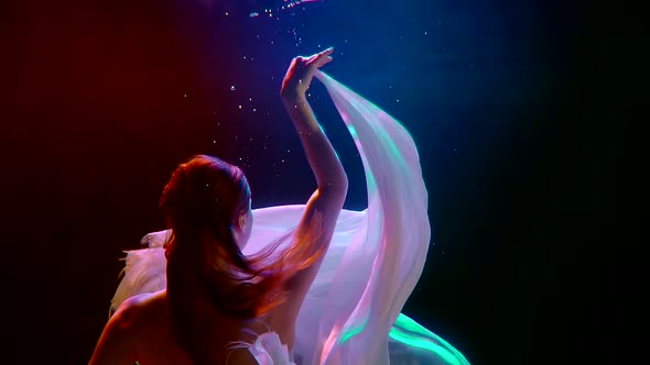 Close-up of a Dark-haired Young Girl, She Is in a Studio Under Water on a Blue Background, She Is