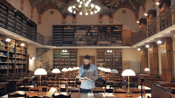 Portrait of a Pensive Bearded Man Student in Sitting at the Library Desk