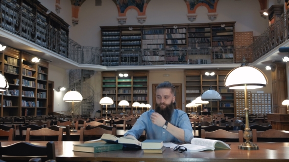 Portrait of a Pensive Bearded Man Student in Sitting at the Library Desk