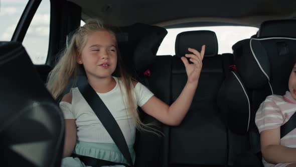 Two caucasian female children riding in the car in the back seat and singing. Shot with RED helium c