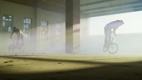 BMX rider in an empty warehouse using smoke grenade