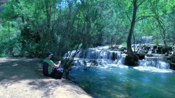 Man is Sitting and Throwing Stones in the Water