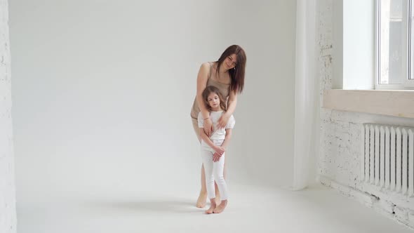 Mom and Daughter Pose in a White Photo Studio for a Photo Shoot