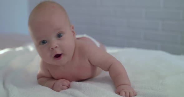 Portrait of Surprised Funny Look of Cute Newborn Baby on Bed