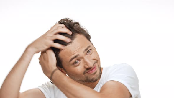 Young Handsome Man Smiling Styling Hair Looking at Camera Over White Background