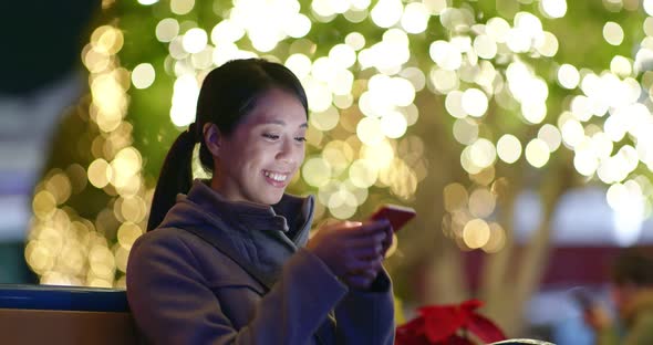 Woman use of mobile phone over Christmas decoration 