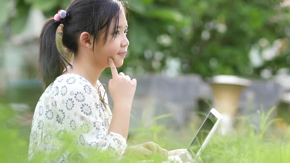 Beautiful Asian Girl Sitting In Park On The Green Grass With Laptop