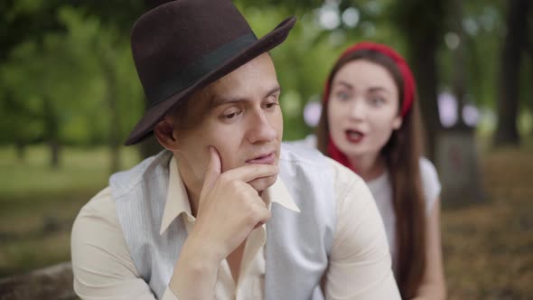 Close-up of Elegant Handsome Boyfriend Holding Face in Hands As Blurred Young Girlfriend Complaining