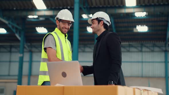 Two Factory Workers Working and Discussing Manufacturing Plan in the Factory