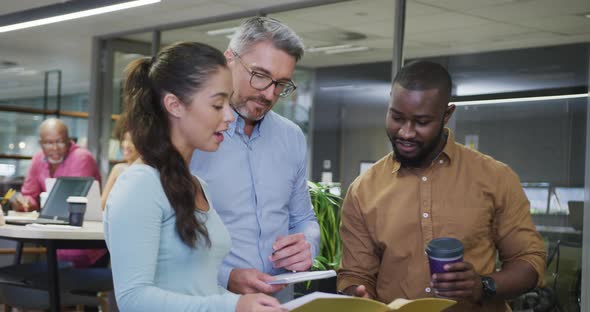 Diverse male and female business colleagues talking and holding documents