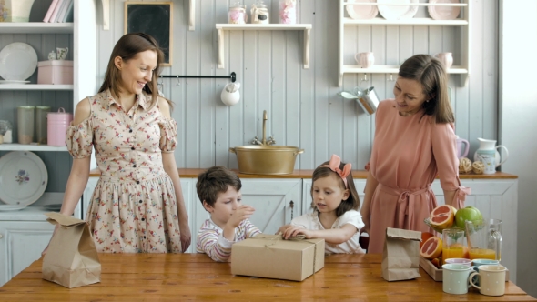 Happy Twins Moms and His Little Daughter Girl and Boy Child Opening Box on Kitchen alt