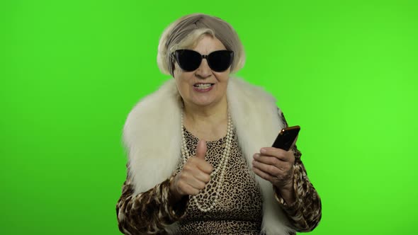 Caucasian Grandmother Woman Using Smartphone, Pointing at Camera with Hand