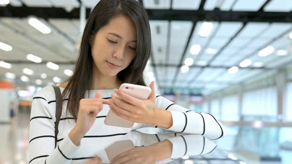 Woman reading cellphone in station hall 