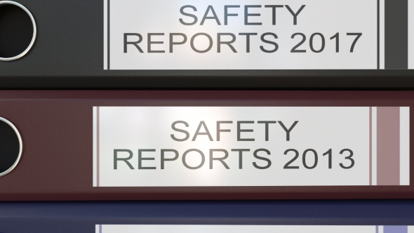 Vertical Stack of Multicolor Office Binders with Safety Reports Tags Different Years