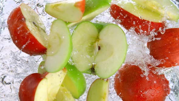 Super Slow Motion Shot of Red and Green Apple Cuts Falling and Splashing Into Water at 1000Fps