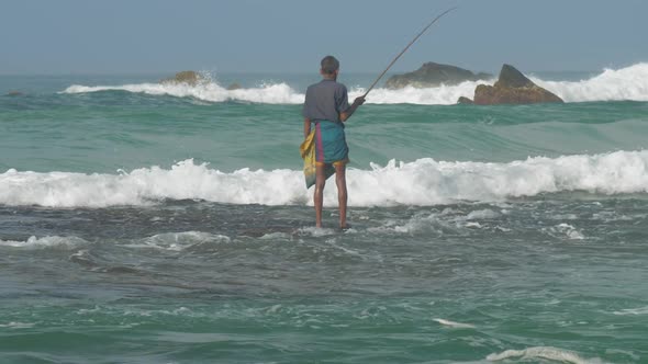 Aged Sinhalese Man Stands in Endless Blue Sea Water with Rod