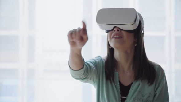 Woman in Vr Head-mounted Display Touching a Virtual Screen