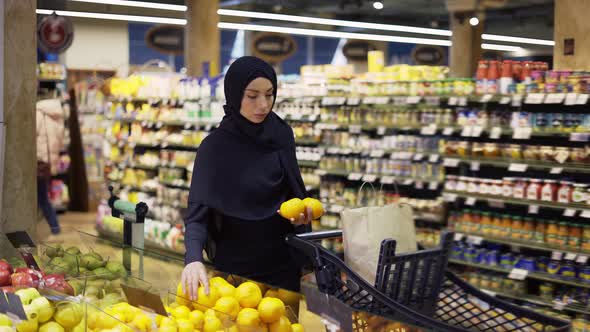 Muslim Woman Shopping for Groceries Taking Lemons From the Fruit Aisle