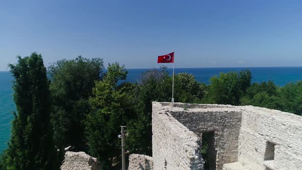 Historical castle and Turkish flag by the sea.