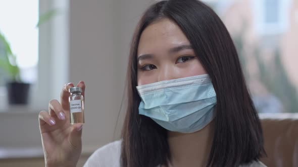 Headshot of Young Asian Woman in Coronavirus Face Mask Turning to Camera Showing Covid19 Vaccine Jab