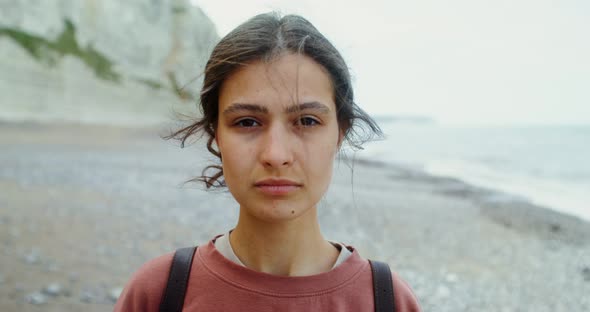 A Young Woman Walks Along a Pebbly Beach Past Sheer Chalk Cliffs