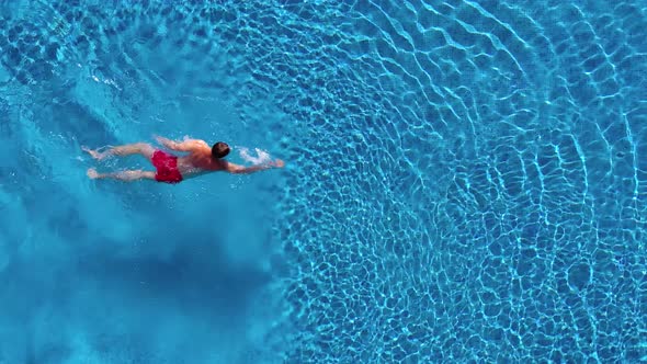 Aerial View of Man in Red Shorts Swims in the Pool