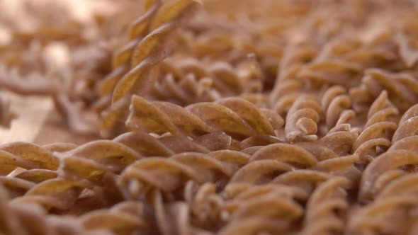 Falling brown whole grain fusilli pasta into a heap in slow motion