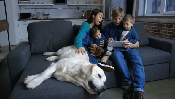 Diverse Family with Puppy Networking on Tablet Pc