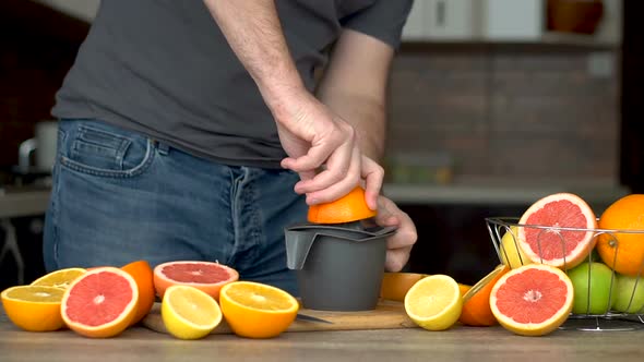 A Man is Squeezes Orange Juice with Citrus Juicer