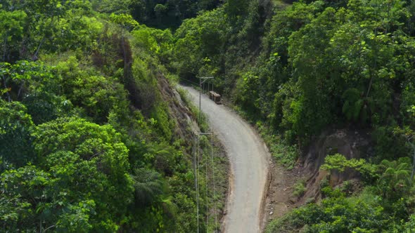 Going over a dirt road with electricity lines alongside and wooden piles