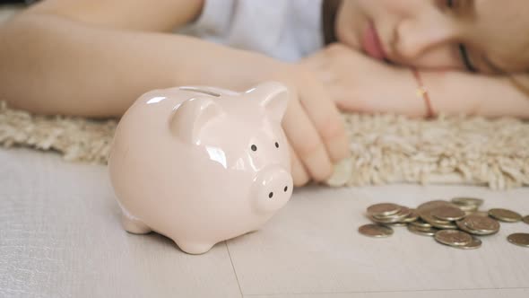 Girl Putting Coin in Piggy Bank Saving Money Concept